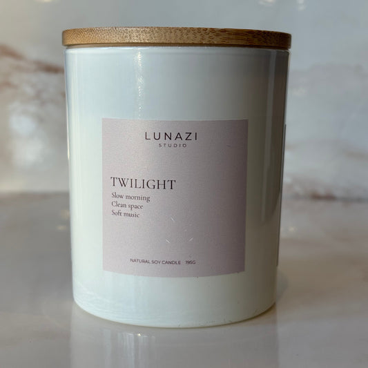 A white candle jar with a light pink label reading 'LUNAZI TWILIGHT' and a gold-toned lid, photographed on a light marble-like surface.